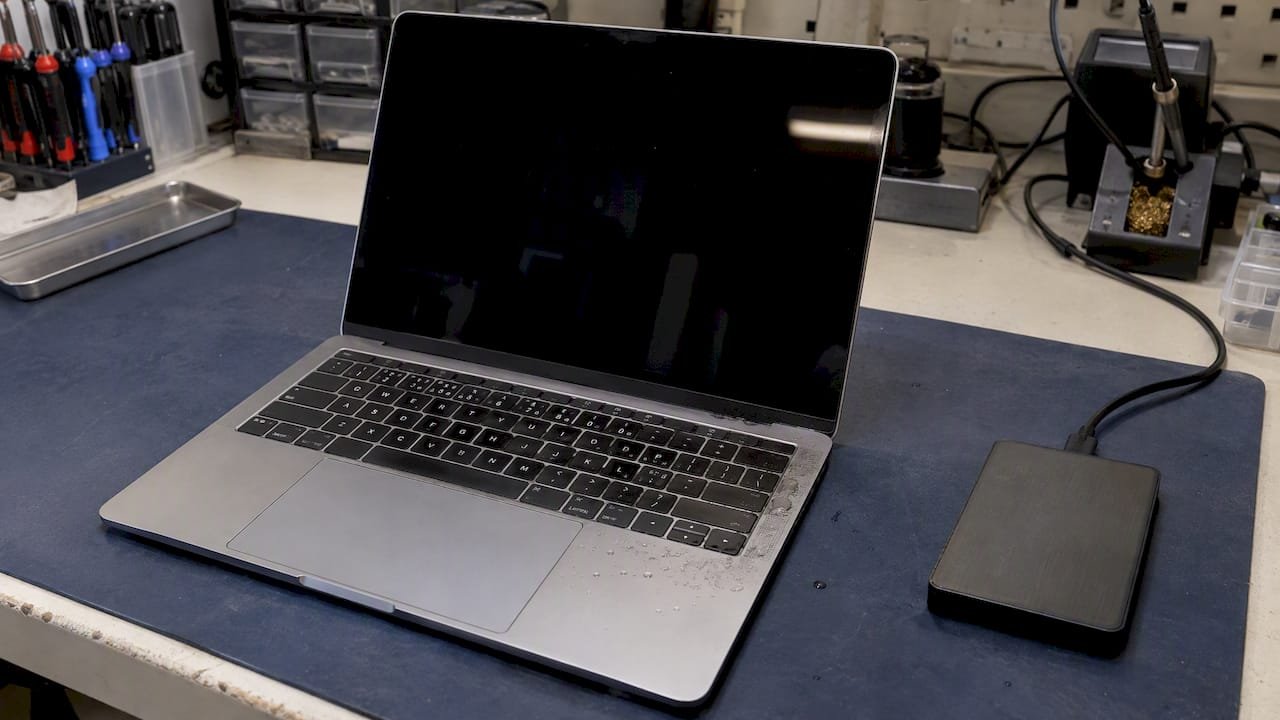 Spilled MacBook beside an external hard drive